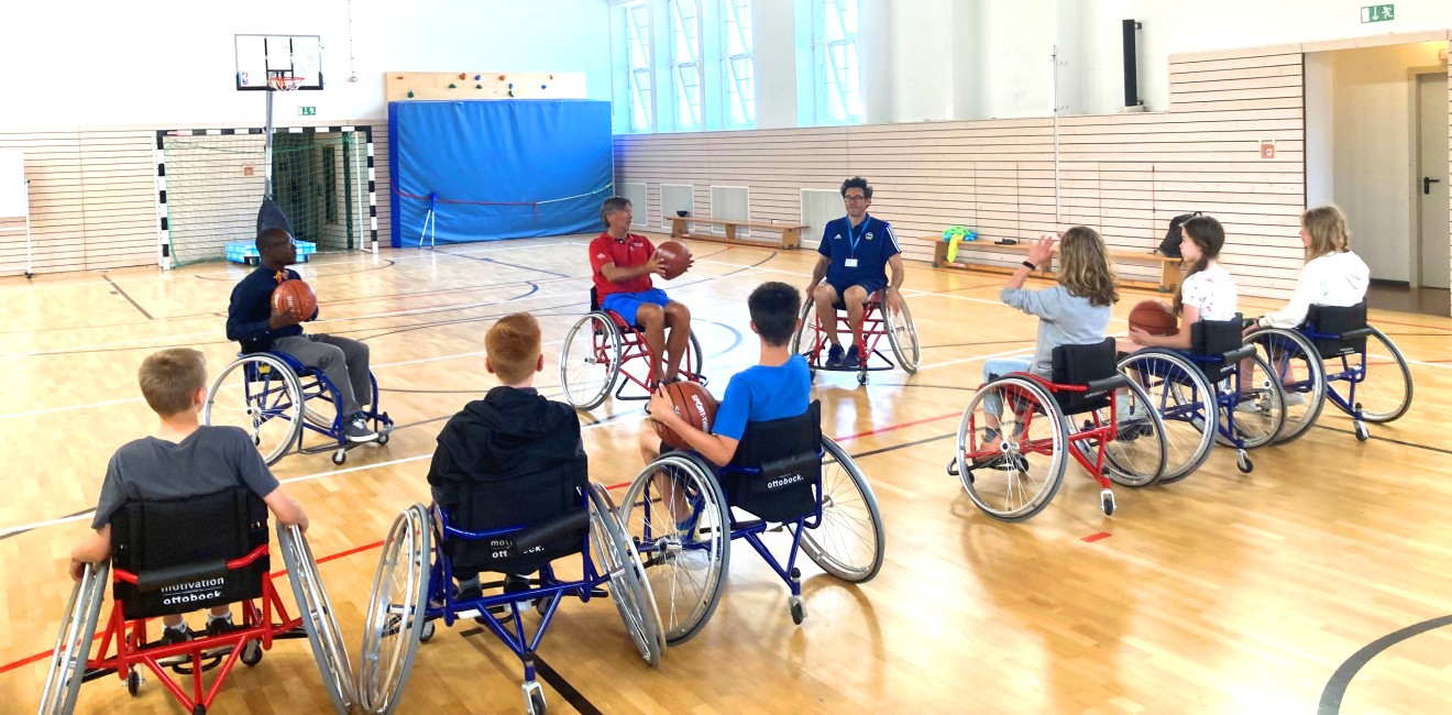 Kinder spielen Rollstuhlbasketball.